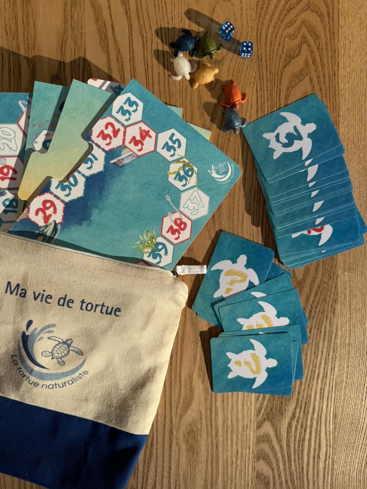 Contenu du kit pédagogique « Ma vie de tortue » : plateau de jeu, cartes, pochette en coton et figurines de tortues